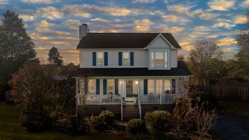 Free A picturesque two-story suburban house with a cozy front porch and beautiful sunset sky. Stock Photo