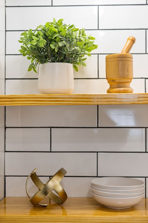 Free Stylish kitchen shelf featuring plant decor, mortar and pestle with modern interior design elements. Stock Photo