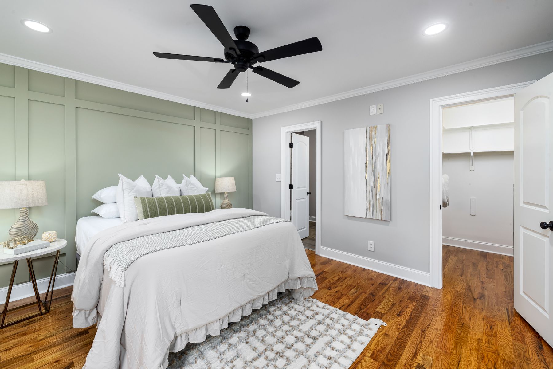 Modern bedroom with green accents, clean-lined furniture, white bedding and warm timber