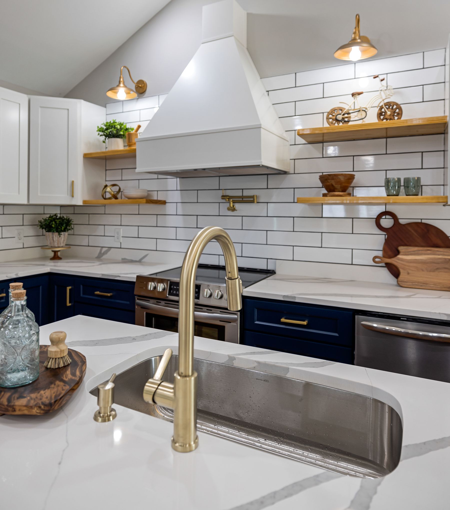 Blue and white kitchen with a warm metal faucet, matching pendant accents and timber shelves