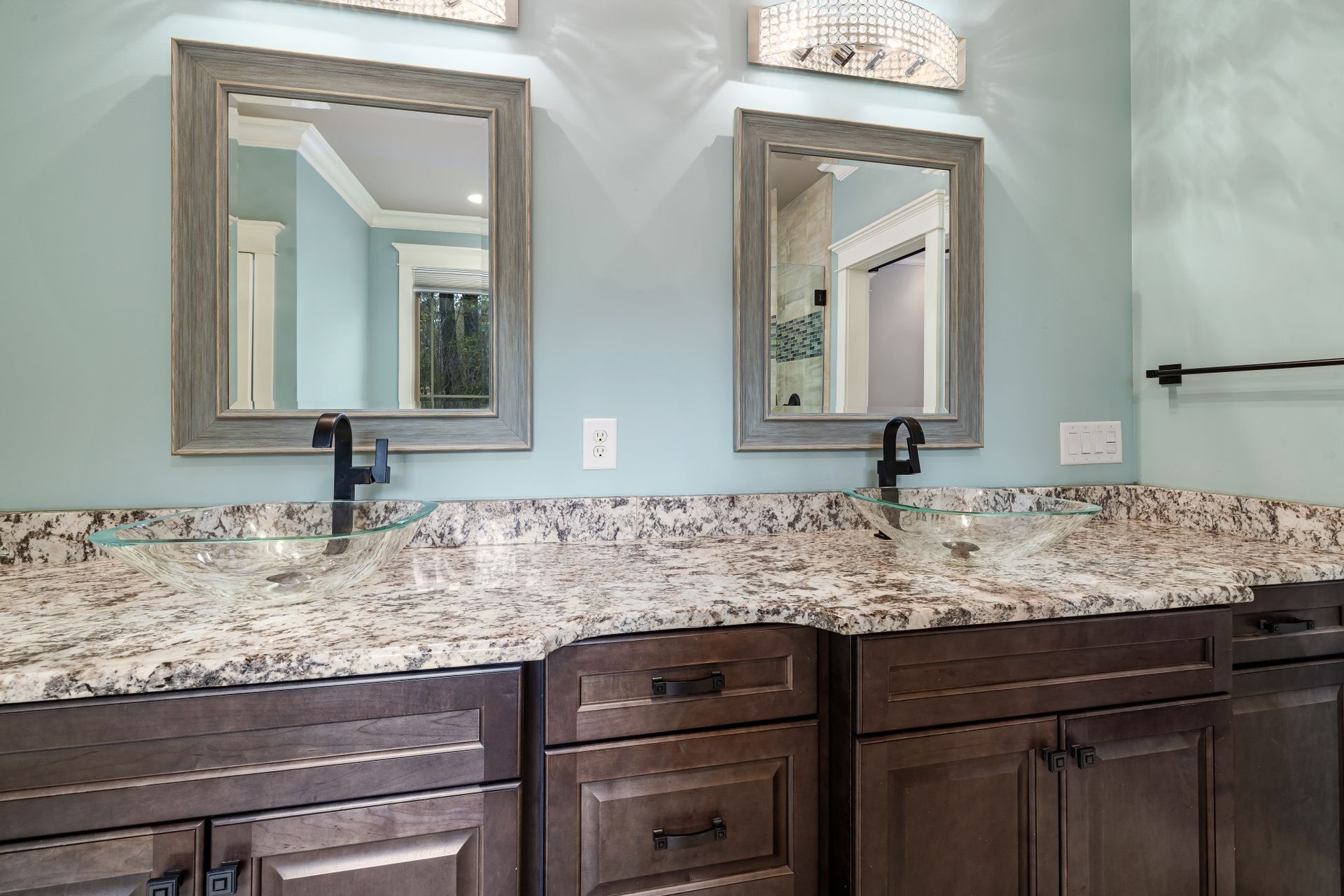 Stylish bathroom featuring dual glass bowl sinks and granite countertops.