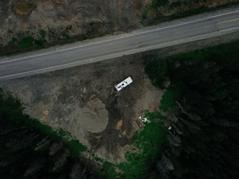 Aerial shot of a campervan parked near a forest road in Gaspé, QC, Canada.