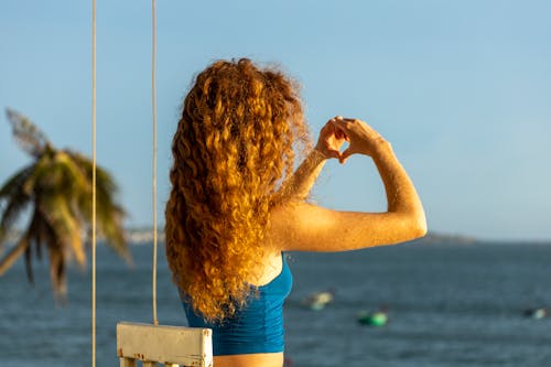 A Woman with Curly Hair Doing a Heart Shape with Her Hands