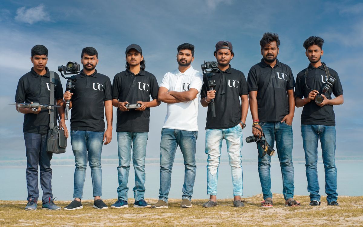 A diverse group of young men standing together outdoors, holding modern filming equipment.