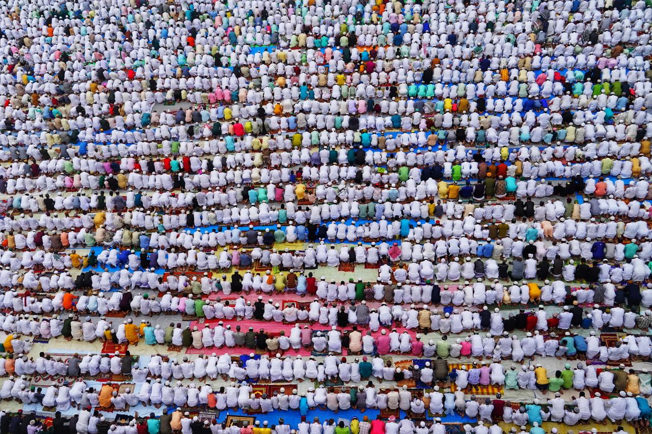 aerial image of a large group of people praying in rows capturing the