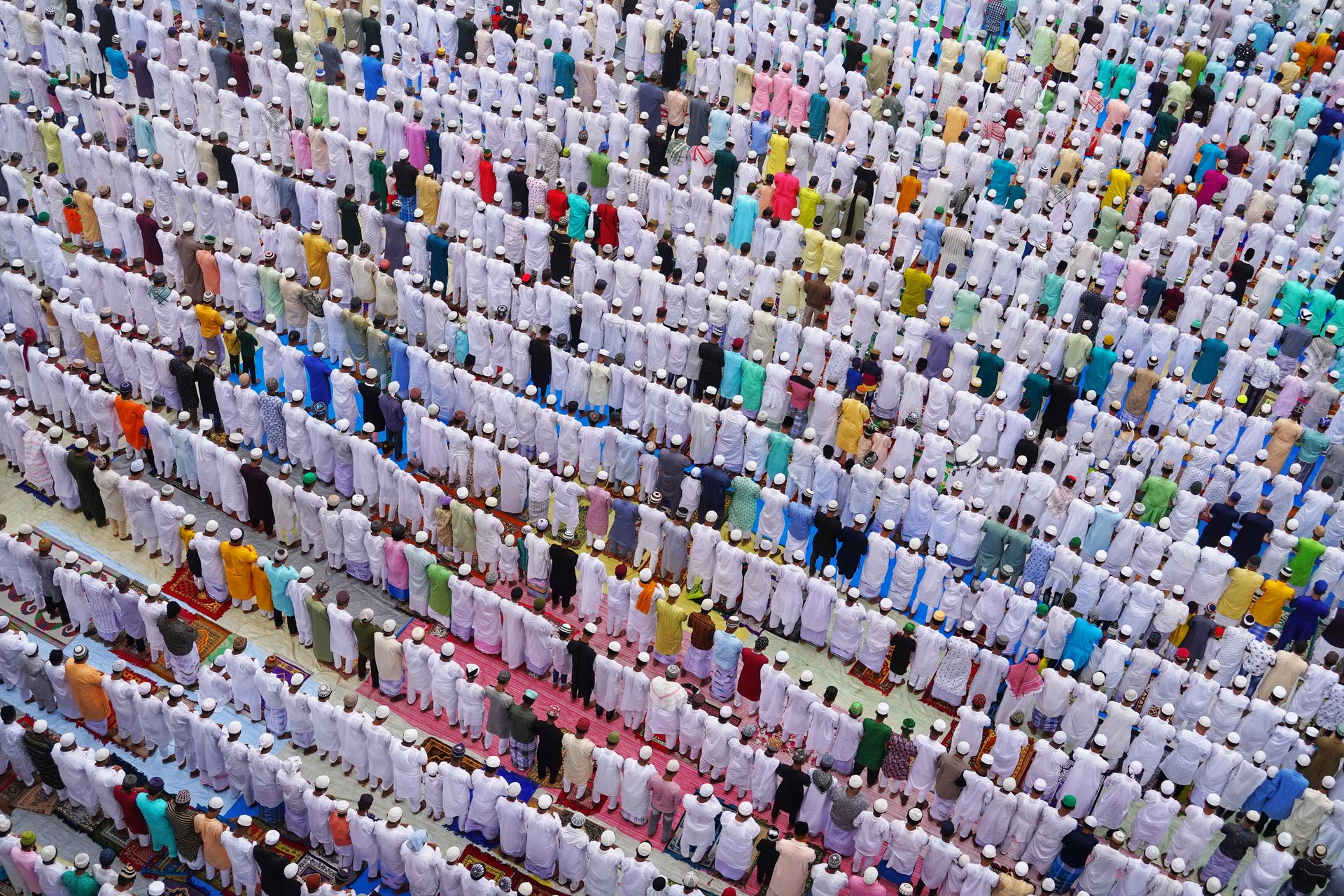 Aerial shot of a large group of people in traditional attire during a prayer in Howrah, India.