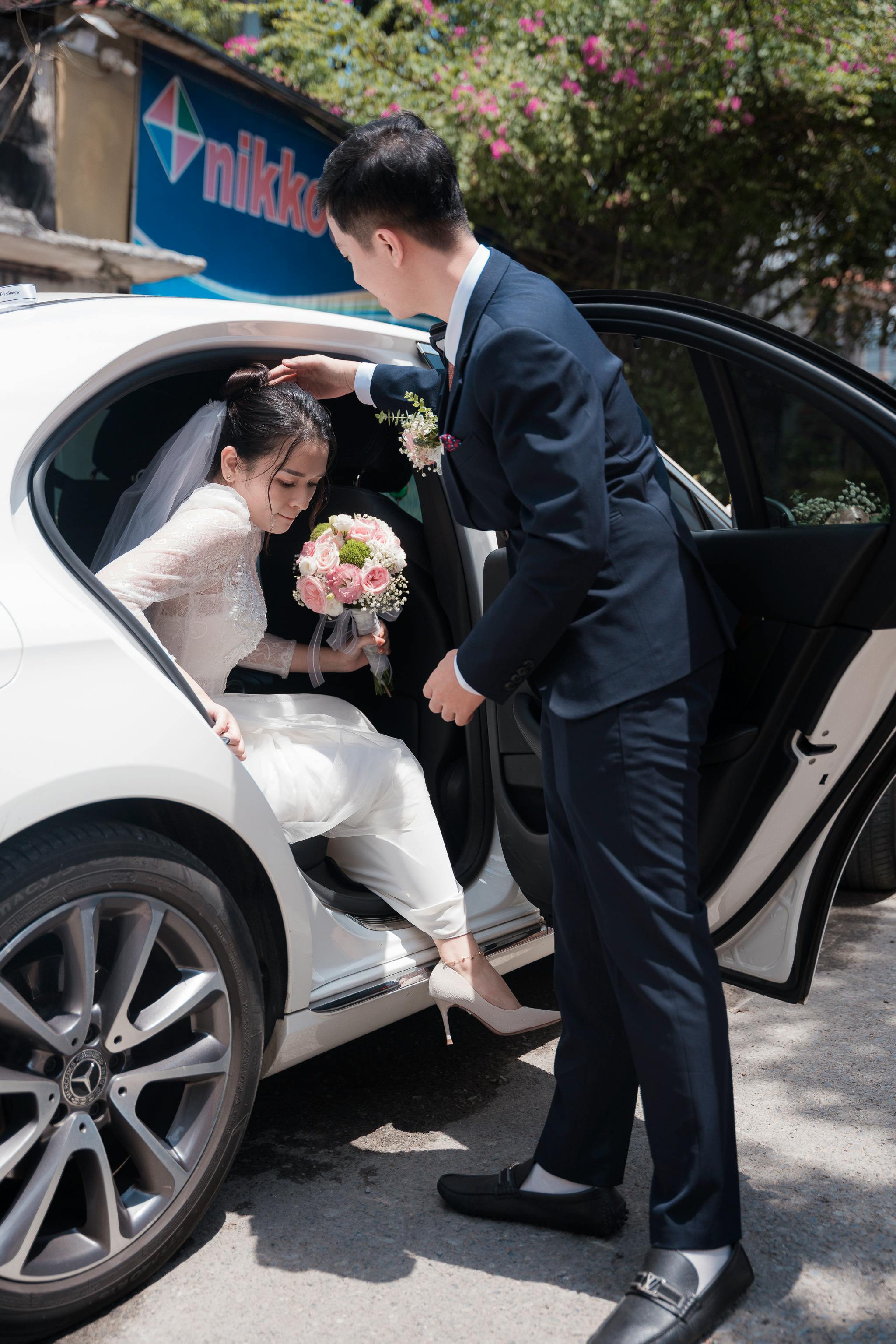 bride holding a bouquet of flowers getting out of the car