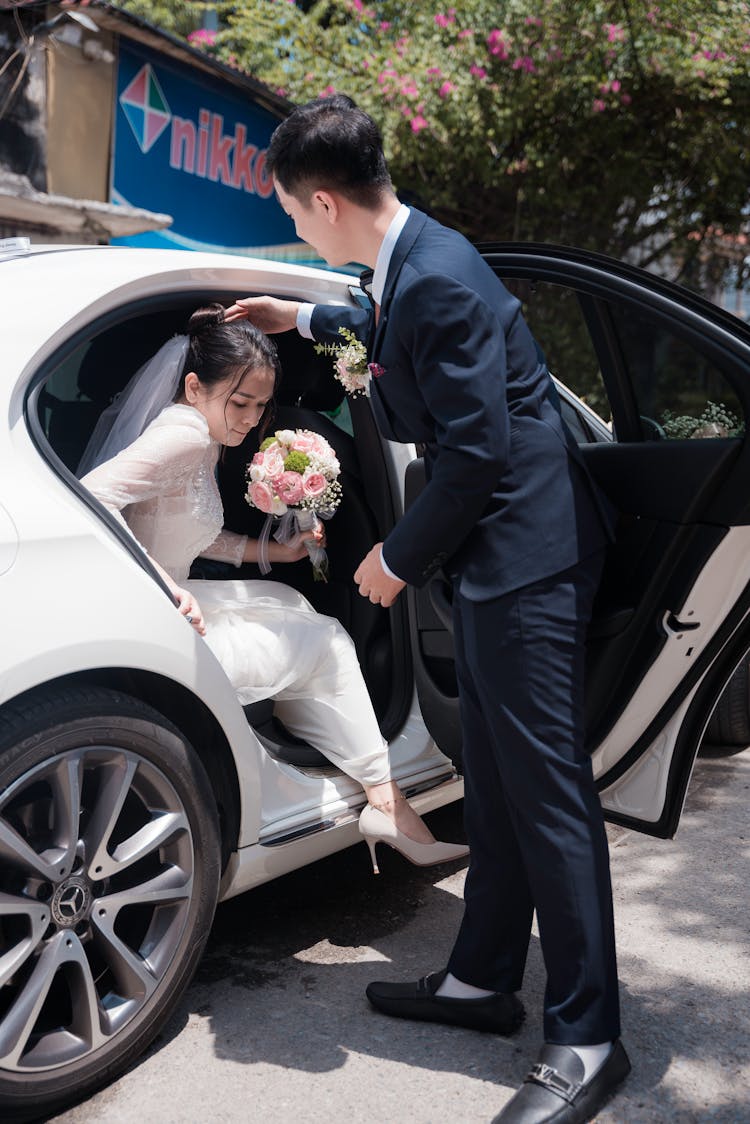 Bride Holding A Bouquet Of Flowers Getting Out Of The Car