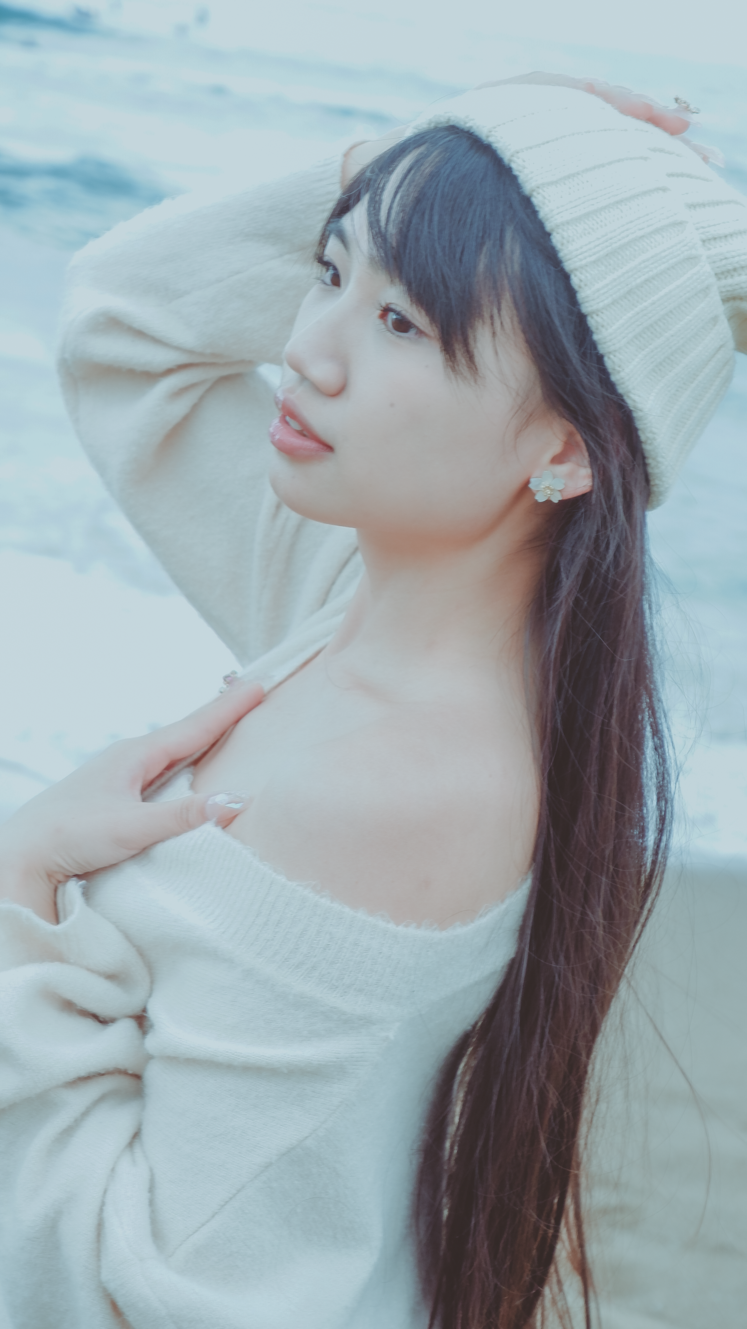 Stylish woman in knitwear enjoys a serene moment at the beach, exuding elegance and warmth.