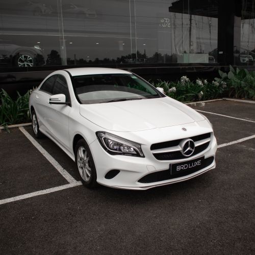 Free Sleek white luxury car parked in front of a modern glass building. Stock Photo