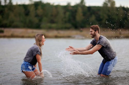 Free Man and Woman Playing on Body of Water Stock Photo