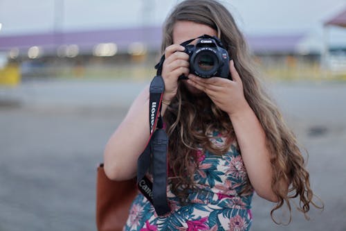 Woman Standing While Holding and Taking Picture from Canon Dslr Camera