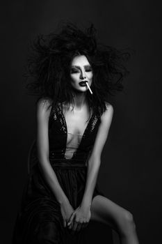 Artistic black and white fashion portrait featuring a woman with intense makeup and cigarette.