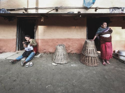Free Mother and grandmother with child outside a rustic home, showcasing traditional lifestyle. Stock Photo