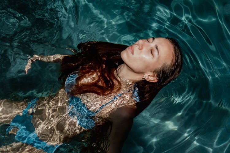 A Woman In Blue Bikini Floating On Water