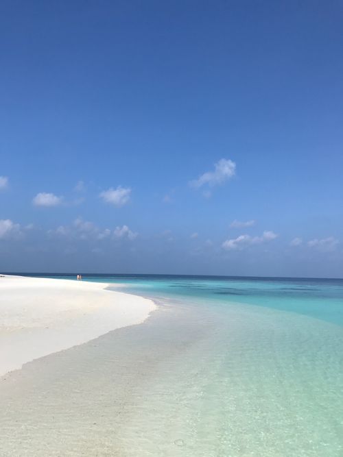 Free Serene seashore with white sand and turquoise ocean under a clear sky. Stock Photo