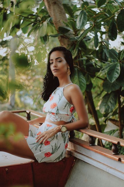 Young woman in floral dress posing outdoors in Brazil's lush greenery.