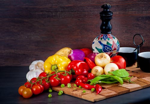 Red Yellow and Green Bell Peppers on Brown Wooden Chopping Board
