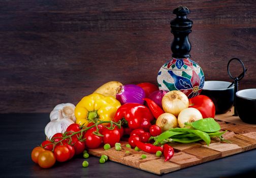 Colorful assortment of fresh vegetables like tomatoes, peppers, and onions on a wooden table.