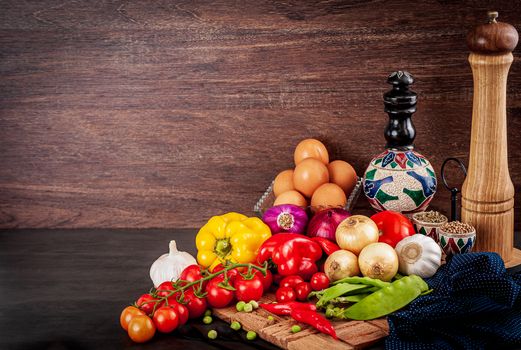 A vibrant arrangement of fresh vegetables, eggs, and spices on a rustic wooden surface.
