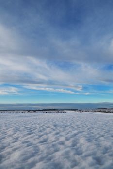 A serene snowy landscape with a wide expanse of blue sky and clouds, perfect for winter travel imagery.