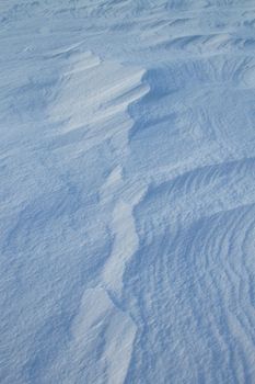 Gently rippling snowdrift patterns create a serene winter landscape.