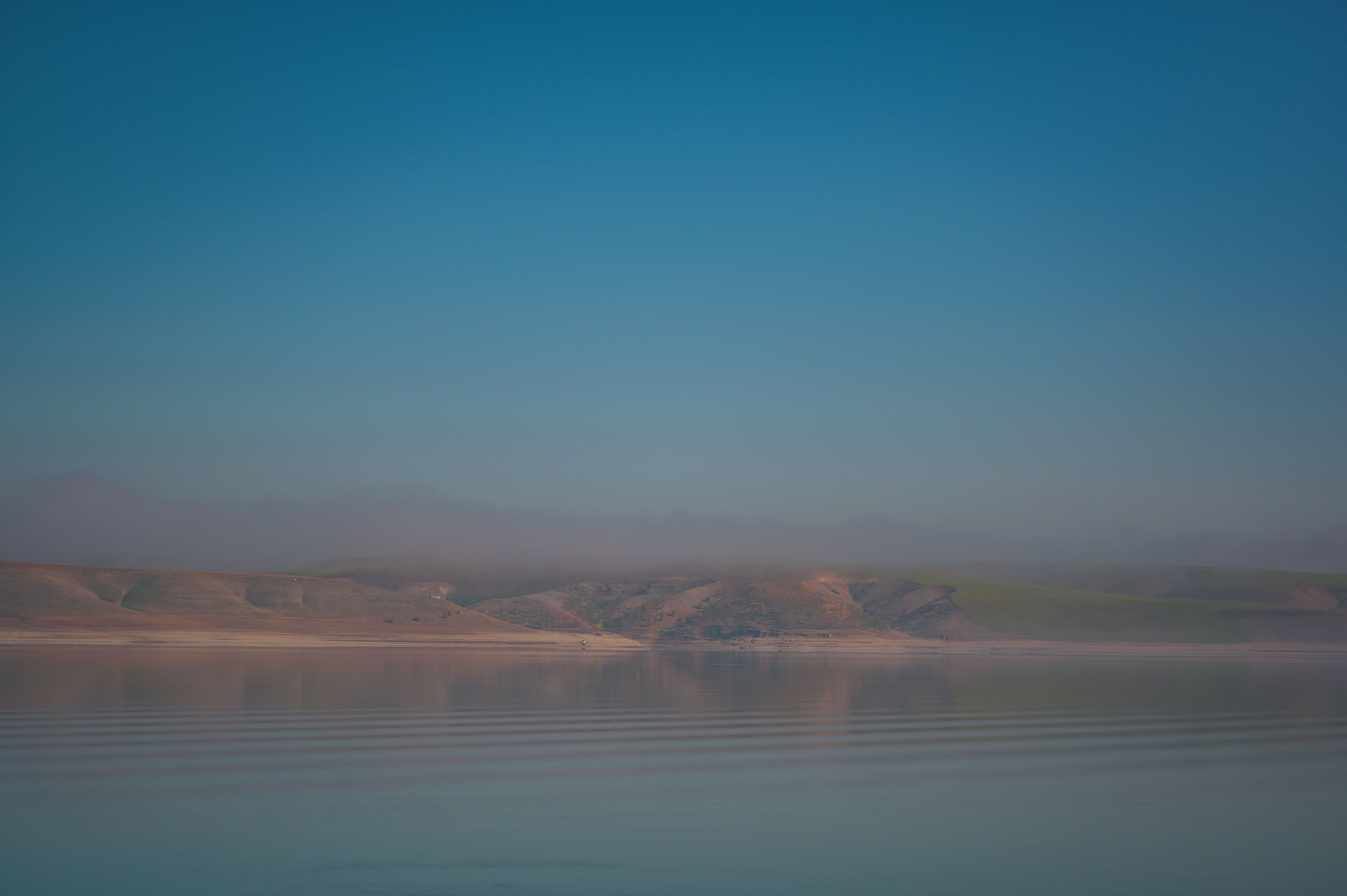 an infinity pool reflecting hills and sky