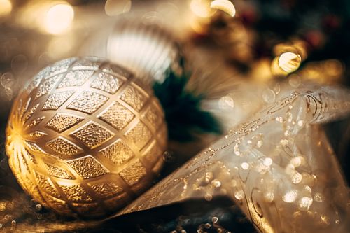 Free Close-up of a gold Christmas ornament with lights glistening in the background. Stock Photo