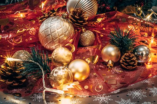 Free Elegant Christmas setup featuring gold ornaments and pine cones on a festive backdrop. Stock Photo