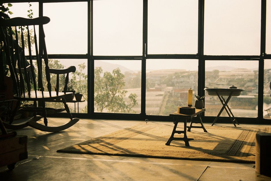 Sunlit room with vintage decor, rocking chair, and scenic view in Đà Lạt, Vietnam.