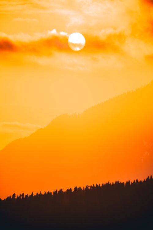 Free A breathtaking sunset scene with a silhouetted mountain and vibrant orange sky, perfect for travel inspiration. Stock Photo