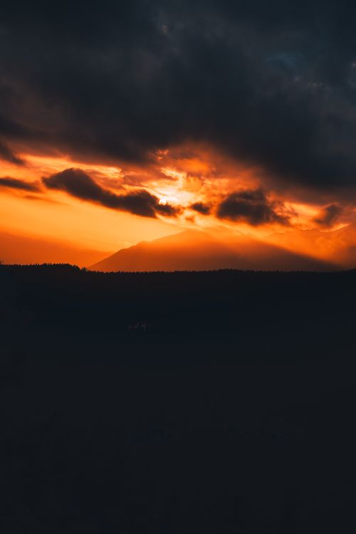 Free Captivating sunset over mountains with dramatic, stormy clouds creating a vibrant silhouette. Stock Photo