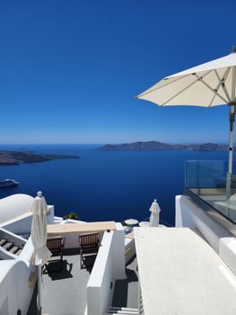 A stunning view of a luxury terrace in Santorini with umbrellas and sea view.