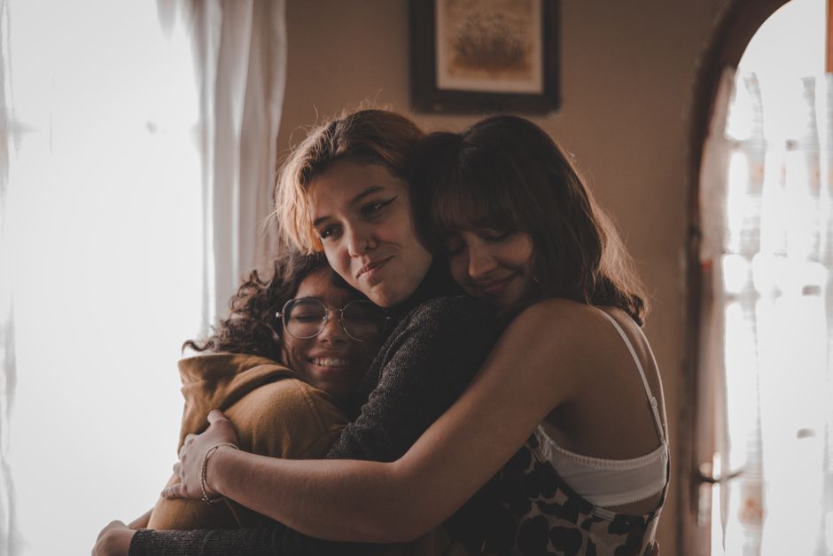 Three friends embracing indoors, a portrait of togetherness