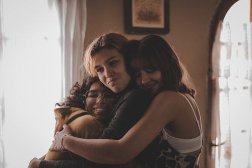 Free A heartwarming portrait of three women hugging indoors, symbolizing friendship and togetherness. Stock Photo
