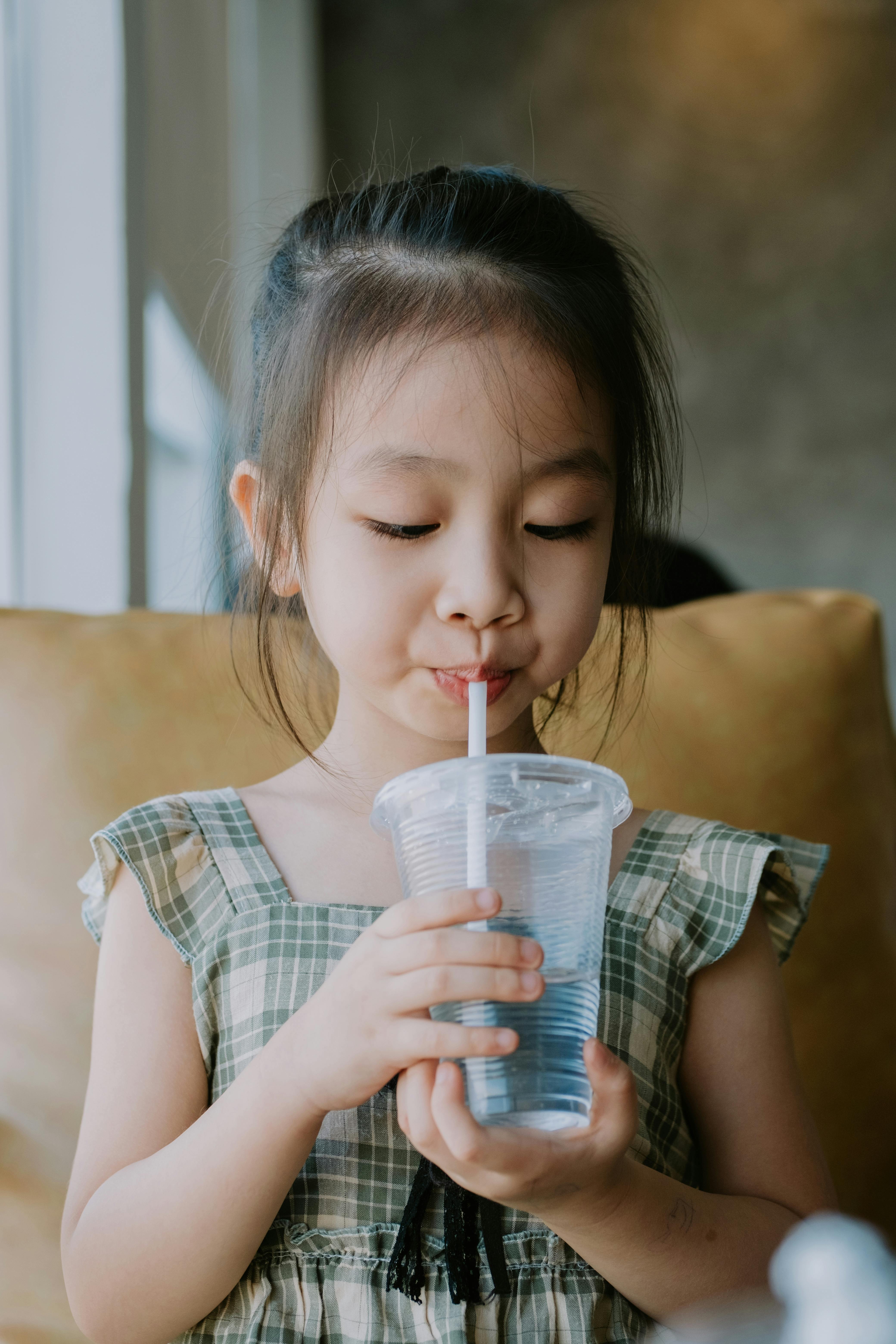 2 year old toddler girl drinking juice from plastic cup with plastic straw  Stock Photo - Alamy