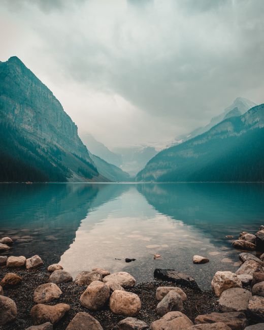 Panoramic view of Lake Louise with mountain reflections and overcast sky.