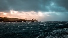 日落时分，岩石岛屿上的灯塔与海景令人惊叹