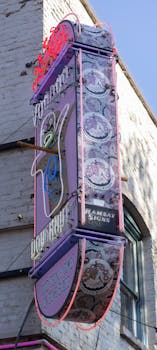 Colorful vintage neon sign outside a doughnut shop in the city, showcasing retro design.