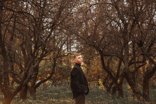 Young Man in a Black Suit Standing among the Trees 