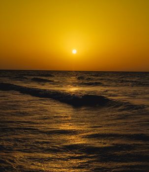 A dramatic sunset over the ocean, capturing golden skies and gentle waves off the coast of Ténès, Algeria.