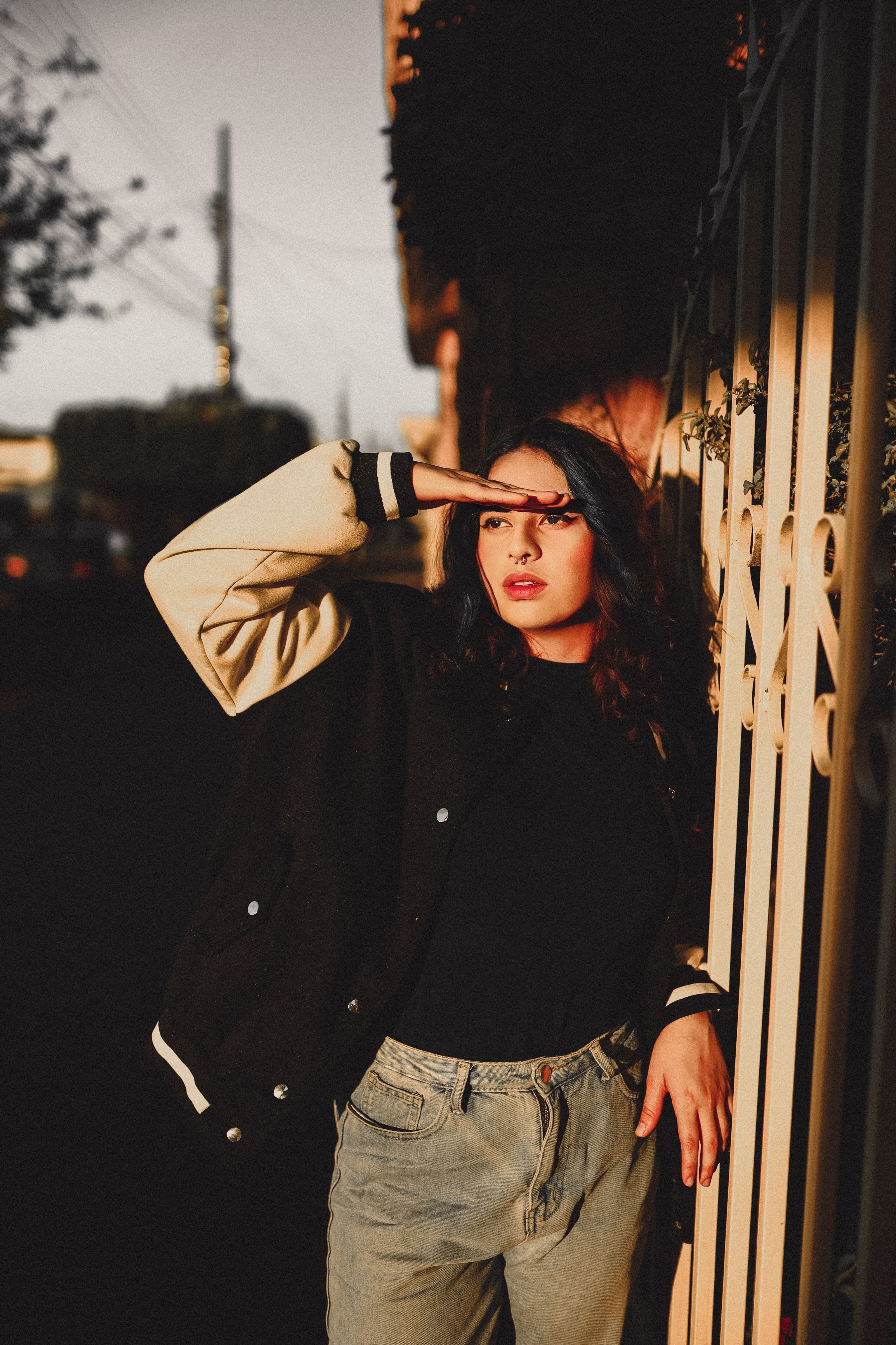 Woman in Black Jacket and Blue Denim Jeans Standing Beside Brown Wooden ...