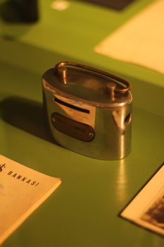 A retro metal bank displayed on a green tabletop in warm lighting, evoking nostalgia.