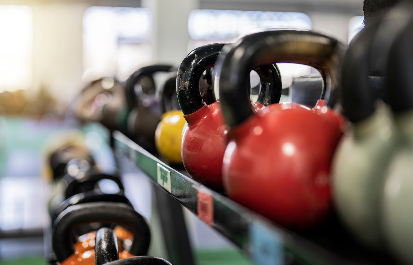 Close-up of colorful kettlebells on a rack in a modern gym indoors.