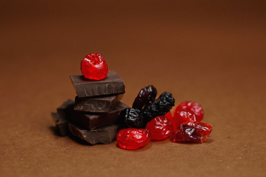 Indulgent dark chocolate pieces with vibrant berries against a rich brown backdrop, perfect for food lovers.