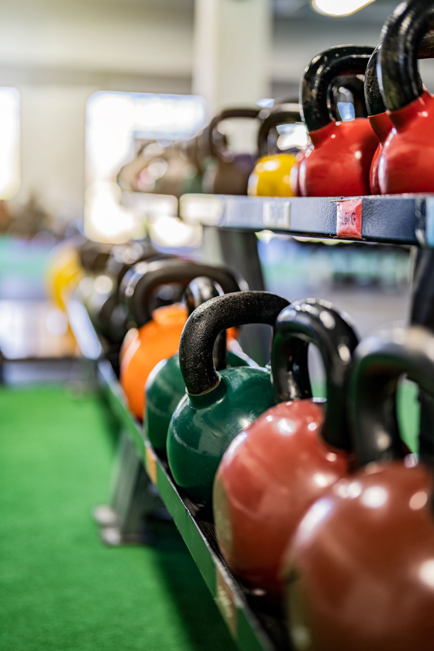Colorful kettlebells organized on a gym rack in the free weights area