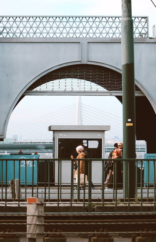 People Walking in City Near an Arch Bridge 