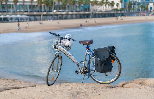 A road bicycle with a basket and bag parked by the beach in Barcelona, Spain.