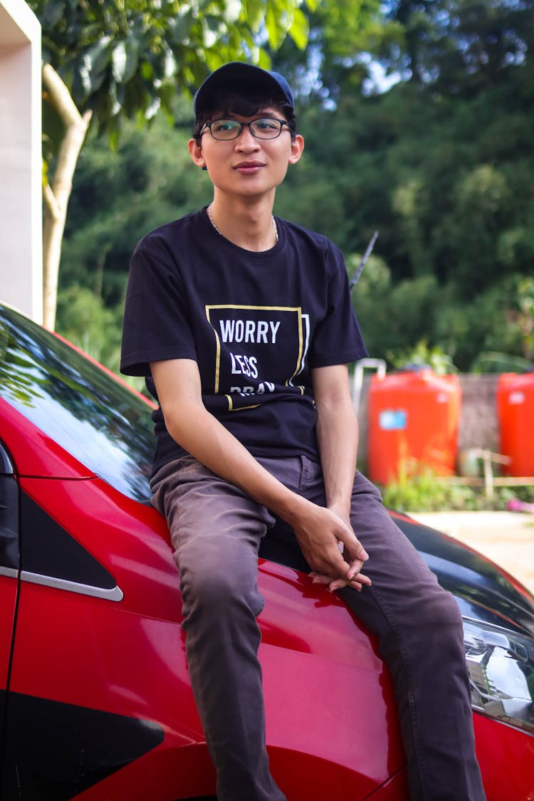 Young Man Sitting On A Car Hood