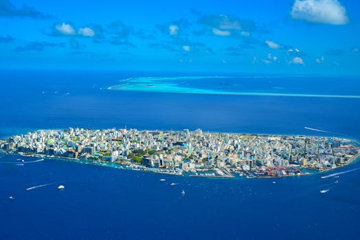 Aerial photo of Malé Island, showcasing the dense cityscape surrounded by the vibrant blue ocean.
